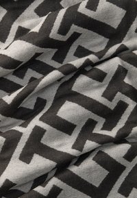 Sort og grå mønstret stof med geometriske former og en blød tekstur. Designet består af sammenflettede vinklede motiver.