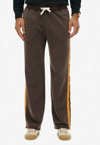 Brune sweats med elastisk talje, hvid snor og sidestriber i lys orange. Fremstillet af blødt, struktureret stof.
