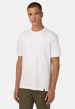 Camiseta blanca de manga corta con cuello redondo, hecha de suave algodón, y que presenta una pequeña etiqueta negra en el dobladillo. Diseño simple y clásico.