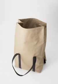 Bežová taška s pevného materiálu, s minimalistickým dizajnom, čiernymi popruhmi a priestranným otvoreným vrchným dielom s vystuženými švami.
