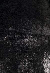 Tissu noir texturé avec un effet scintillant, présentant des intensités variables de reflets argentés. Surface lisse avec des motifs subtils.