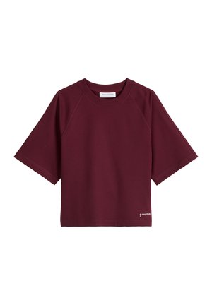 Kurzärmeliges, burgunderrotes T-Shirt mit Rundhalsausschnitt, Raglanärmeln und kleinem weißen Schriftzug nahe dem unteren Saum vor weißem Hintergrund.