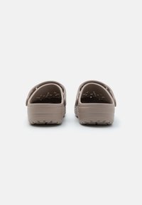 Heled pruunid vahtsusksud ümmarguse disainiga, külgede avad ventileerimiseks, pehme tekstuur ja tugev mustriga tald.