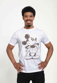 Hvid bomulds t-shirt med et stort sort og gr�åt skitse af Mickey Mouse. Rund halsudskæring og korte ærmer. Ensfarvet baggrund.