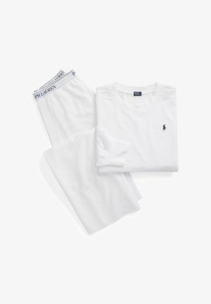 Camicia bianca a maniche lunghe con logo Polo Ralph Lauren blu navy piegata accanto a pantaloni bianchi con fascia in vita firmata Polo Ralph Lauren.