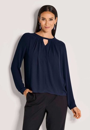 Marineblaue Bluse mit langen Ärmeln, Schlüssel-ausschnitt, gefalteter Vorderseite und weicher Textur. Kombination mit schwarzen Hosen. Elegante und lässige Passform.