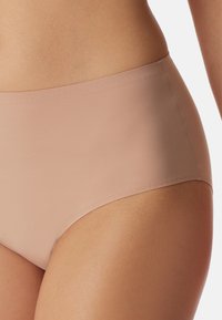 Beige højtaljede trusser lavet af glat stof. Har et sømløst design med en let glans og ingen synlige sømme langs kanterne.
