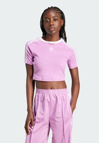 Light purple cropped athletic t-shirt with white trim, short sleeves, and Adidas logo; paired with matching light purple sweatpants.
