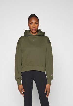 Sudadera corta de color verde oliva con un logo en el frente y puños acanalados, combinada con leggings negros. Tejido suave y casual, diseño con capucha.