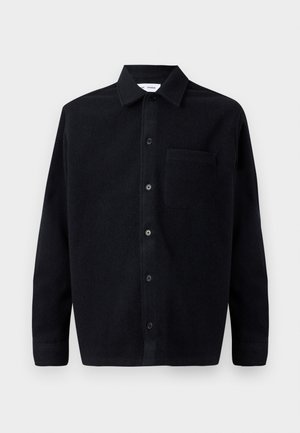Black wool shirt with a button-down collar, long sleeves, and a patch pocket on the left side. Smooth texture with subtle softness.