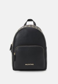 Svart läderryggsäck med rundad design, detaljer i guld, en framficka med dragkedja och ett handtag på toppen. Har en logo på framsidan.