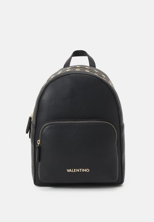 Sac à dos en cuir noir avec un design arrondi, des accents en métal doré, une poche zippée à l'avant et une poignée supérieure. Présente un logo à l'avant.