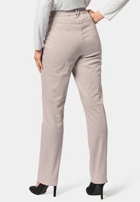 Lichtbeige broek met een elastische tailleband en een rechte pijpontwerp. De stof lijkt soepel met een subtiele glans. Zwarte hoge hakken zijn zichtbaar.