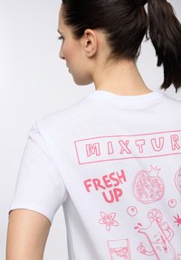 T-shirt bianco a maniche corte con grafica rosa che presenta il testo "MIXTURE" e "FRESH UP", con illustrazioni di frutti e una bevanda sul retro.
