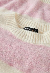 Sweter w paski w jasnoróżowym i kremowym kolorze, wykonany z miękkiej tkaniny, z prążkowanym dekoltem i metką z napisem "LMTD" wewnątrz.