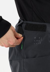 Pantaloni cargo grigi con chiusura in Velcro in vita, caratterizzati da un design elegante e un logo visibile sul tessuto.