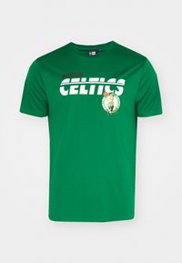 Zöld, rövid ujjú póló, amelyen a "BOSTON CELTICS" felirat fehér és piros színben található. Egy grafikát is tartalmaz, amelyen egy kobold kosárlabdát tart.