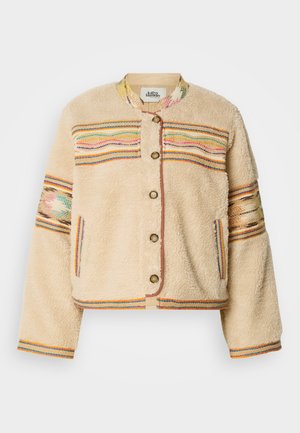 Veste en fausse fourrure crème avec des accents tissés colorés, bouton à l'avant et poignets côtelés. Présente une broderie décorative sur les épaules et les manches.
