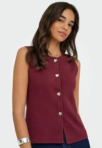 Burgundia värvi ilma varrukateta topp, millel on ümar kaelus ja viis metallist südamekujulist nööbi esiosas; sile tekstuur ja lõdva disain.