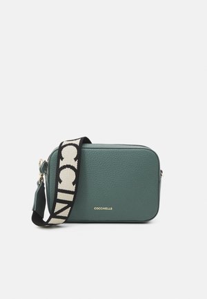 Turkooizen leren crossbodytas met een gestructureerde afwerking, rechthoekige vorm, gouden logo en een stoffen band met een contrasterend patroon.