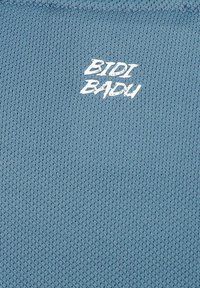 Tela texturizada azul con el texto impreso en blanco "BIDI BADU" en la parte frontal. El material parece transpirable con un patrón de tejido ligero.