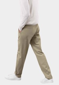 Pantalones caqui de algodón con ajuste recto, que presentan bolsillos laterales y detalles de costura sutiles, combinados con zapatillas blancas.