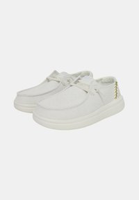Zapatos casuales blancos hechos de tejido texturizado con suela de goma lisa. Presenta un sutil detalle de costura y diseño de cordones.