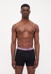 Black boxer briefs made from a soft material, featuring a purple waistband with "BJÖRN BORG" text. Designed with a snug fit and no visible patterns.
