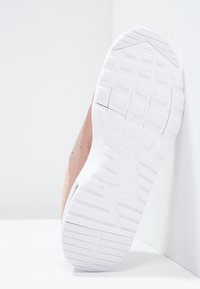 Skoled med vitt mönster och "Nike"-logotyp, lutad mot vit golv- och väggbakgrund.