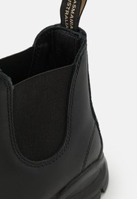 Schwarze Leder Chelsea-Stiefel mit elastischen Seitenteilen, einer strukturierten Oberfläche und einer Zuglasche mit Markenlogo auf der Rückseite.