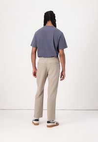 T-shirt en coton bleu marine ajusté avec des manches courtes associé à un pantalon beige léger avec une taille élastique et des poches arrière.