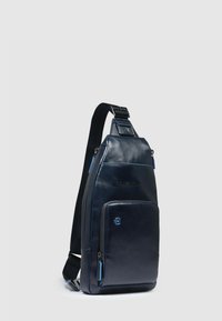 Borsa a tracolla in pelle blu navy con una texture liscia, dotata di tasca frontale e dettagli con cerniera blu. Tracolla regolabile e design elegante.