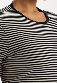 Black and white striped t-shirt with a round neckline and black trim. The fabric appears soft with visible stretch and smooth texture.