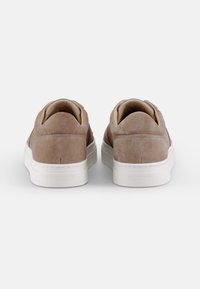 Brune semskede sneakers med en glat overflade, hvid gummisål, rund tå og minimalistisk design. Har et logo på hælen.