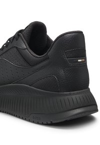 Mustat tennarit, joissa on teksturoitu nahkainen päällinen, kontrastiväriset verkkokoristeet ja uurrettu kumipohja. Ominaisuutena minimalistinen logodetaili.