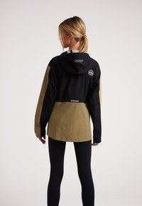 Svart och khaki jacka med huva, med en logotyp på baksidan, långärmad och med avslappnad passform. Slät material, utan dekoration.