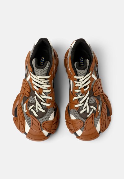 Chunky Sneakers mit einer Mischung aus braunem Leder, grauem Mesh und weißen Akzenten. Auffällige Gummi-Überzüge, strukturierte Sohlen und cremfarbene Schnürsenkel.