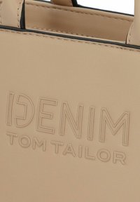 Beige synthetische handtas met reliëf "DENIM TOM TAILOR" logo, minimalistisch ontwerp en zwarte stikselaccenten. Soepele textuur.