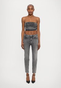 Lühendatud hall denimpaita koos logoga, millele on sobitatud vormitud hallid teksad ja mustad terava ninaga kontsad. Minimalistlik disain, sile tekstuur.