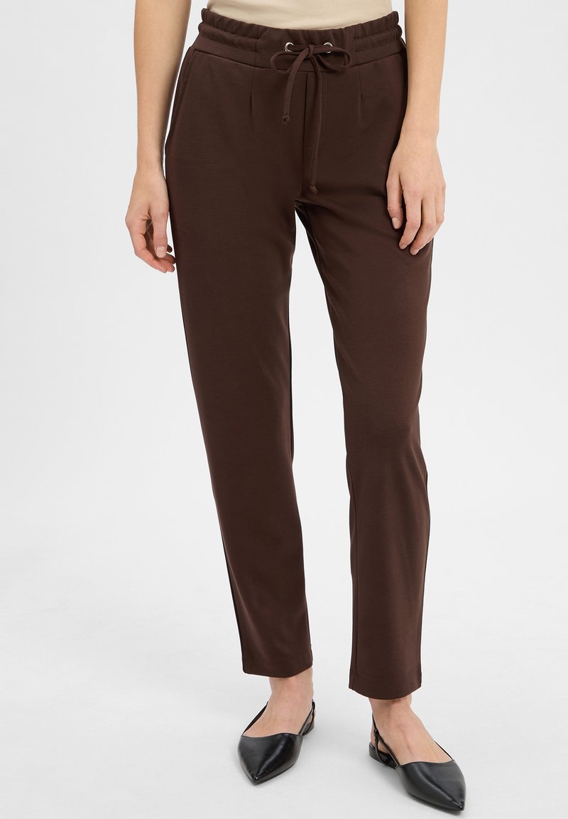 Brązowe, dopasowane joggery z elastycznym paskiem i bocznymi kieszeniami, wykonane z miękkiego, elastycznego materiału. Bez widocznych wzorów ani akcentów.