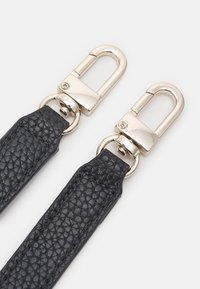 Bracelet en cuir noir avec une finition texturée, équipé de fermoirs métalliques dorés, rectangulaires et brillants.