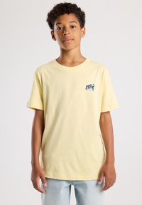 Geel katoenen T-shirt met korte mouwen en een ronde hals, voorzien van een klein "SURF"-graphic in blauw en groen op de linkerborst.