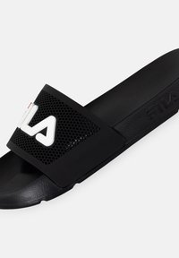 Musta liukumäen sandaali, jossa on rei'itetty päällinen ja kohokuvioitu logo. Sandaalissa on litteä pohja ja teksturoitu pohja mukavuutta varten.