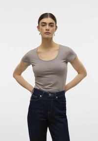 T-shirt med kort ärm och rundad hals i ljusgrått tyg, kombinerad med mörkblå jeans i klassisk passform med synliga sömnadsdetaljer.
