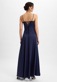 Navy satijnen maxi-jurk met dunne spaghettibandjes, een gedetailleerde achterkant met kant en een vloeiende rok. Glad textuur en elegante silhouet.