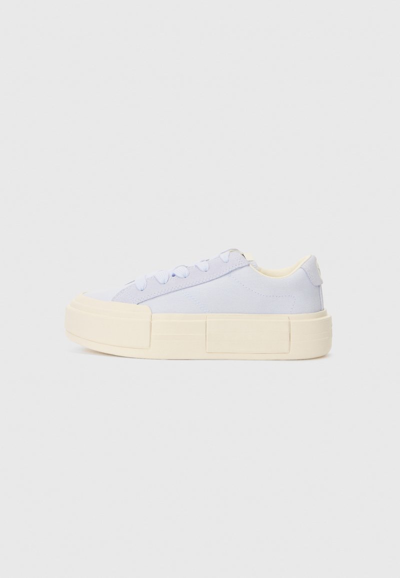 Light blue canvas sneakers with a thick cream-colored platform sole, round toe, and matching laces, featuring minimalistic design details.