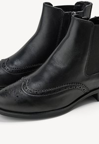 Svart läderankelstövlar med brogue-design, med perforerade detaljer, elastiska sidopaneler och en låg staplad klack.