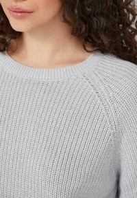 Hellgrauer gestrickter Pullover mit einem strukturierten Muster, ausgestattet mit einem gerippten Kragen und Raglanärmeln. Weicher Stoff mit lässiger Passform.