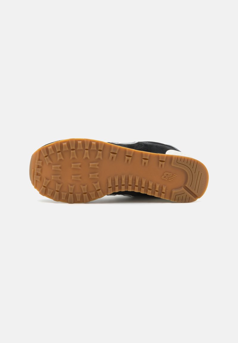 Schuhsohle aus Gummi mit dicken, ausgeprägten Profil; Obermaterial aus dunklem schwarzem Textil und helleren Akzenten, die im Design für Kontrast sorgen.