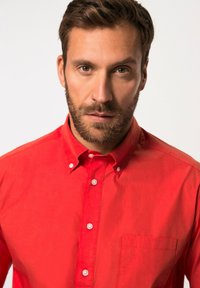 Camisa roja de manga corta con cuello, botones en la parte delantera y un bolsillo en el pecho; textura suave con botones blancos y un corte clásico.